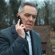 Custe o Que Custar: Elenco, Sinopse, trailer e Tudo Que Você Precisa Saber sobre o novo sucesso da Netflix James Nesbitt ao telefone em cena tensa de Custe o Que Custar, nova série de suspense de Harlan Coben na Netflix, estreia 1º de janeiro de 2026